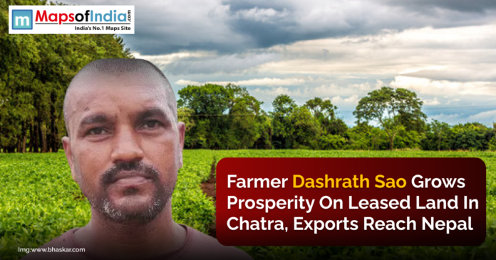 Farmer Dashrath Sao stands in front of lush green farmland under a cloudy sky.