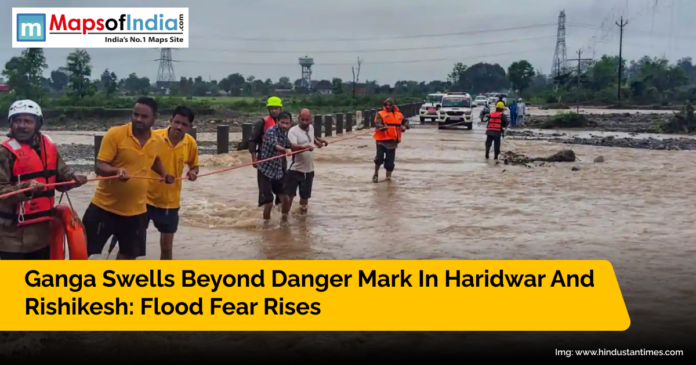 Rescue teams help stranded people cross flooded streets as the Ganga river rises beyond danger mark in Haridwar and Rishikesh after heavy rains.