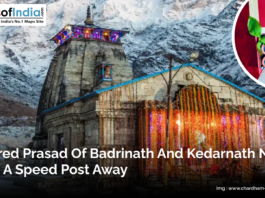 Illuminated Badrinath temple in the Himalayas with snow-covered mountains in the background. Inset shows a box of sacred prasad ready for delivery by speed post. Caption highlights that devotees can now receive prasad from Badrinath and Kedarnath conveniently at home.
