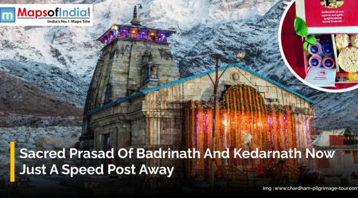 Sacred Prasad of Badrinath and Kedarnath Now Just a Speed Post Away Illuminated Badrinath temple in the Himalayas with snow-covered mountains in the background. Inset shows a box of sacred prasad ready for delivery by speed post. Caption highlights that devotees can now receive prasad from Badrinath and Kedarnath conveniently at home.