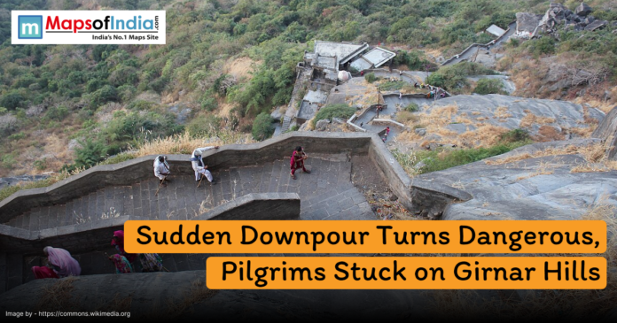 Pilgrims climbing the steep stone steps of Girnar Hills in Gujarat, with surrounding greenery, where sudden downpour has left many stranded as highlighted in the news headline.