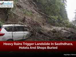 A landslide in Sasthdhara triggered by heavy rains, with a car trapped under debris, fallen trees, and mud covering the road