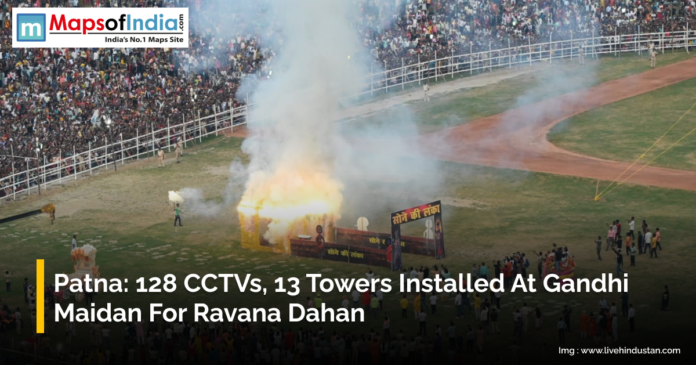 A large crowd watches the burning of a Ravana effigy at Gandhi Maidan in Patna during Ravana Dahan, with smoke rising and the event monitored by installed CCTV cameras and towers.
