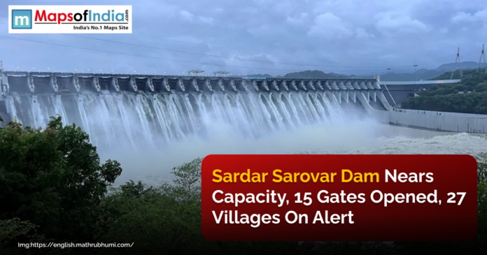 Sardar Sarovar Dam releasing water with multiple gates open, as authorities issue an alert for 27 villages due to rising water levels.