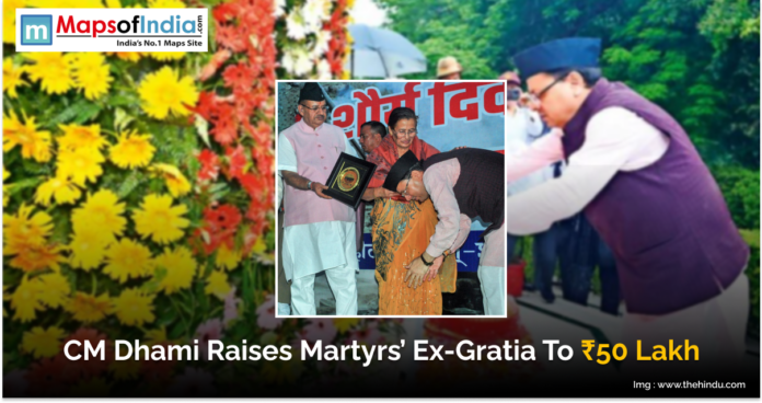 Image showing Uttarakhand Chief Minister Pushkar Singh Dhami honoring the family of a martyr during an event. The text on the image reads “CM Dhami Raises Martyrs’ Ex-Gratia To ₹50 Lakh.” The background includes flowers and the Maps of India logo.