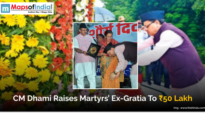 CM Dhami Raises Martyrs’ Ex-Gratia to ₹50 Lakh Image showing Uttarakhand Chief Minister Pushkar Singh Dhami honoring the family of a martyr during an event. The text on the image reads “CM Dhami Raises Martyrs’ Ex-Gratia To ₹50 Lakh.” The background includes flowers and the Maps of India logo.