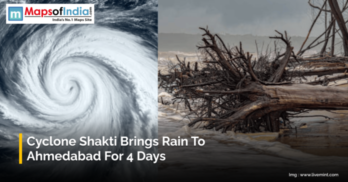 Image showing a powerful cyclone formation over the ocean and fallen trees along a flooded coastline. The text reads “Cyclone Shakti Brings Rain to Ahmedabad for 4 Days,” with the Maps of India logo at the top.