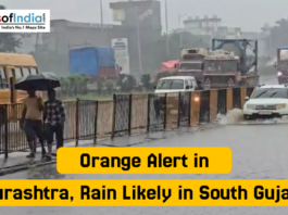 Orange Alert in Saurashtra, Rain Likely in South Gujarat Vehicles move slowly through a waterlogged road as people walk under umbrellas during heavy rain in Gujarat, with the headline “Orange Alert in Saurashtra, Rain Likely in South Gujarat”