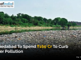 A polluted river in Ahmedabad filled with waste, with trees and buildings visible in the background.