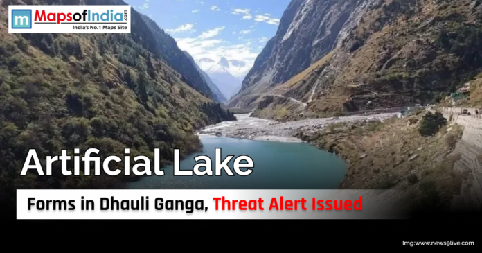 Artificial Lake Forms in Dhauli Ganga, Threat Alert Issued View of an artificial lake formed in the Dhauli Ganga river valley surrounded by steep mountain slopes, with a threat alert issued due to potential flooding risks.