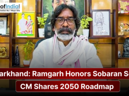 A man in traditional white attire sits before a decorated shelf with portraits, alongside a banner reading “Jharkhand: Ramgarh Honors Sobaran Soren; CM Shares 2050 Roadmap.”