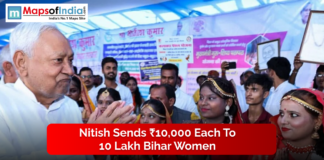 Nitish Sends ₹10,000 Each to 10 Lakh Bihar Women A senior official interacts with a group of women dressed in traditional attire at a public event, with banners displayed in the background.