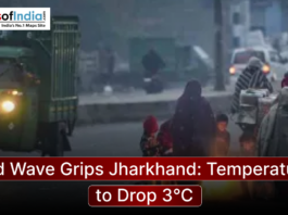 People wrapped in blankets gather around a small fire on a foggy street in Jharkhand as temperatures drop during a severe cold wave, with vehicles passing nearby.