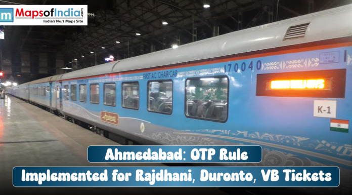 Ahmedabad: OTP Rule Implemented for Rajdhani, Duronto, VB Tickets A blue and grey train (Rajdhani Express) car at a station platform, with a text overlay reading: "Ahmedabad: OTP Rule Implemented for Rajdhani, Duronto, VB Tickets".