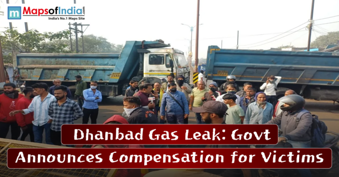 Crowd gathers near parked trucks in Dhanbad as officials inspect the site following a gas leak; headline highlights government compensation for victims.