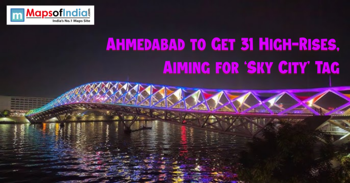 Night view of Ahmedabad’s illuminated footbridge over the Sabarmati River with colorful lights, highlighting news about the city planning 31 new high-rise buildings to earn the ‘Sky City’ tag.