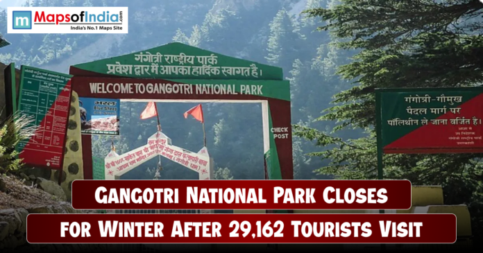 Entrance gate of Gangotri National Park surrounded by dense green forests and mountains, with a headline overlay stating “Gangotri National Park Closes for Winter After 29,162 Tourists Visit,” and the Maps of India logo at the top left corner.