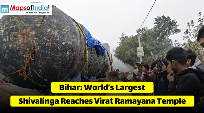 Bihar: World’s Largest Shivalinga Reaches Virat Ramayana Temple An image showing a massive, black stone Shivalinga being transported on a large trailer, surrounded by a crowd of people. Yellow text overlays read: "Bihar: World’s Largest Shivalinga Reaches Virat Ramayana Temple." The "Maps of India" logo is in the top left corner.