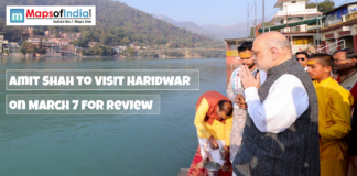 Amit Shah to Visit Haridwar on March 7 for Review Amit Shah offers prayers by the Ganga river in Haridwar, with text overlay announcing his visit on March 7 for a review