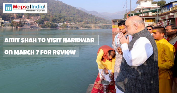 Amit Shah offers prayers by the Ganga river in Haridwar, with text overlay announcing his visit on March 7 for a review