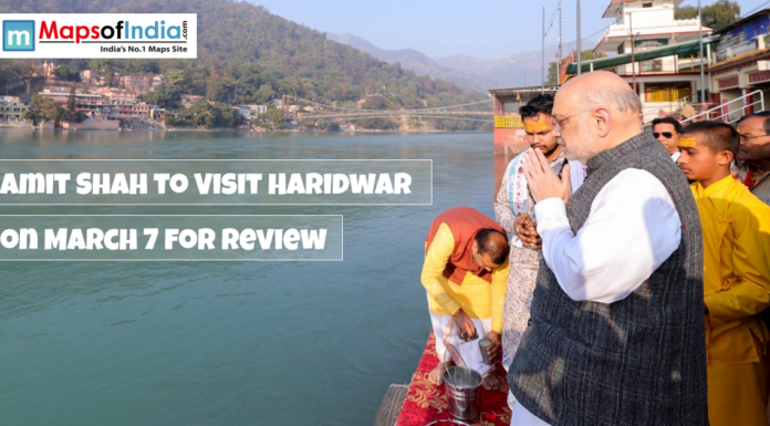 Amit Shah to Visit Haridwar on March 7 for Review Amit Shah offers prayers by the Ganga river in Haridwar, with text overlay announcing his visit on March 7 for a review