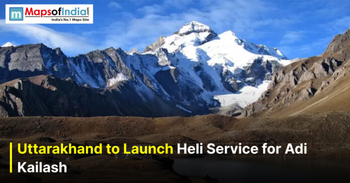 Snow-capped Adi Kailash peak in Uttarakhand under a clear blue sky with text overlay reading “Uttarakhand to Launch Heli Service for Adi Kailash” and Maps of India logo in the corner.