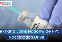 Jharkhand Joins Nationwide HPV Vaccination Drive An image featuring a close-up of a gloved hand holding an HPV vaccine vial being accessed by a syringe, with a text overlay that reads "Jharkhand Joins Nationwide HPV Vaccination Drive" and a Maps of India logo.