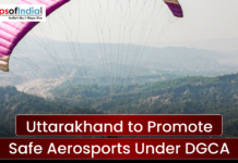 Uttarakhand to Promote Safe Aerosports Under DGCA A wide scenic shot of a person paragliding over a lush green mountainous valley under a clear sky. A text banner reads "Uttarakhand to Promote Safe Aerosports Under DGCA" with the Maps of India logo in the top left.