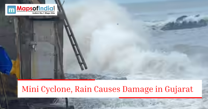 Large sea waves crashing near a coastal structure with text about mini cyclone and rain damage in Gujarat.