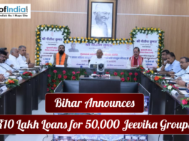 Government meeting in Bihar where officials announce ₹10 lakh loans for 50,000 Jeevika groups, with a portrait of Mahatma Gandhi displayed in the background.