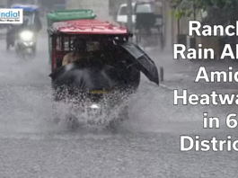 Auto-rickshaw driving through heavy rain on a flooded road in Ranchi with text overlay about rain alert amid heatwave in six districts.