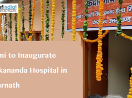 A building decorated with marigold garlands and a banner in Hindi, with text overlaying "Dhami to Inaugurate Vivekananda Hospital in Kedarnath" and the Maps of India logo.