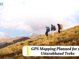 Trekkers hiking across a mountain slope in Uttarakhand with snow-capped peaks in the background, highlighting GPS mapping plans for 100 trekking routes.