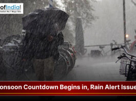 Heavy rainfall during monsoon season with a rain alert warning and people using umbrellas on a city street.